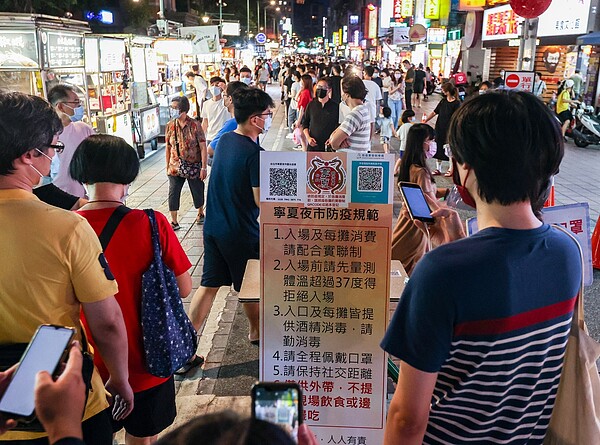 台北市寧夏夜市「微解封」後人潮湧現，消費者謹守防疫規定，落實實聯制，無人邊走邊吃。記者曾原信／攝影 