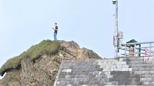 合歡山地區今人潮明顯變多，因地標「武嶺亭」封閉，竟有民眾為拍照取景攀爬岩石登高。圖／讀者提供