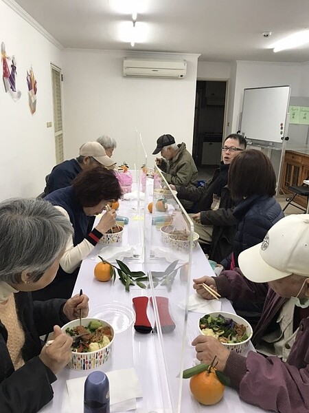 敦安里的長者共餐活動，餐桌上貼心的擺上塑膠板防疫。圖／王復提供