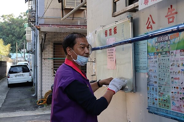 鮑里長於里長辦公室外整理公告欄及留言板的資訊。圖/楊家威攝