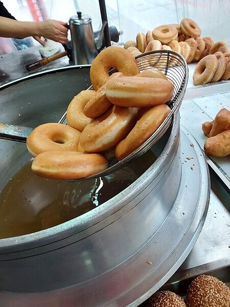 甜甜圈沾上獨門糖粉，油炸到酥脆焦黃。圖／曾慎昭攝