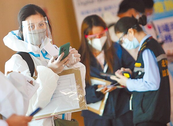 隨著各國疫苗開打,疫情卻沒有降溫,學者憂心可能重演1918年西班牙流感的第三波大流行。圖為24日在桃園機場入境管制區內,身穿防護裝備的菲籍移工準備通關入境。(范揚光攝)