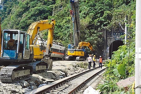 
台鐵太魯閣號事故列車，第6節車廂暫時放置在隧道口、鐵道路線旁空處，等待新的轉向架運抵裝上，才能復軌拖曳離開。（王志偉攝）
