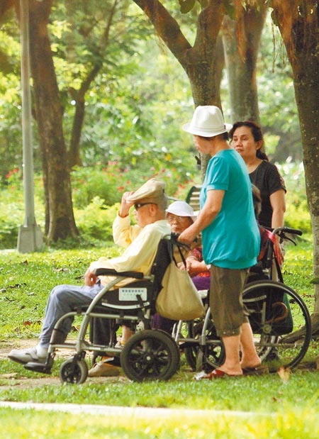 因應照顧家人需求，據調查逾7成5上班族願意申請「長期照顧安排假」。圖為看護人員帶著需要照顧的老人到公園活動。（本報資料照片）