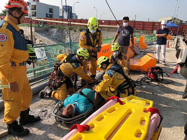 台中市北屯區經貿東路的工地20日下午發生工安意外，蘇姓工人連人帶車，掉落15公尺深的工地，消防隊利用低索、吊車，協助蘇脫困。圖／記者陳宏睿翻攝