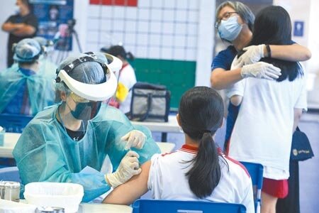 全台校園接種BNT疫苗第2天,北市泰北中學23日在校內體育館施打,有學生懼怕接種,學校義工連忙上前擁抱安撫。(張鎧乙攝)