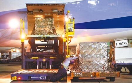 我方自購的第8批莫德納疫苗,9日凌晨運抵桃園機場,貨機停妥後,地勤人員卸下裝載疫苗的冷凍貨櫃。(范揚光攝)