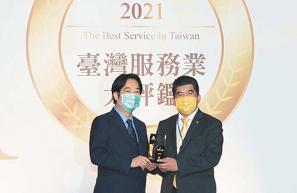 永慶房屋獲2021「臺灣服務業大評鑑」服務金獎肯定,締造九連霸紀錄,永慶房屋總經理吳良治(右)從副總統賴清德手中接下獎盃。圖/永慶提供