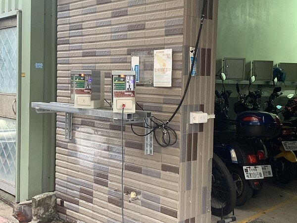 桃園市大園區有移工宿舍在門口設立了一排電動自行車投幣式充電樁，市議員游吾和發現部分電源是從2樓牽電線設置，質疑其安全問題。圖／市議員游吾和提供
