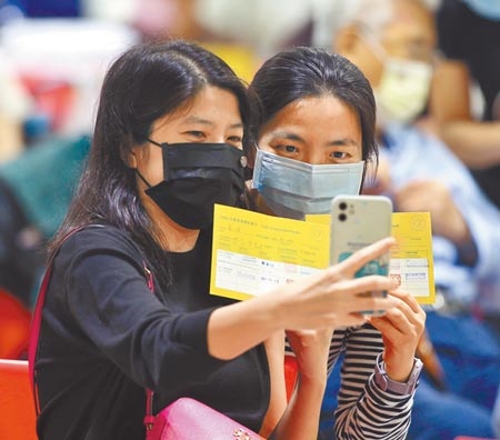 第14輪COVID-19疫苗20日開放混打，預約民眾上午至台北市花博施打站接種莫德納疫苗，兩位民眾施打完後一起手機自拍留念。（陳怡誠攝）