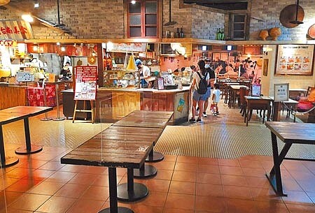 中央宣布27日降為二級警戒,但雙北仍禁止餐廳內用,新北市百貨公司美食街25日桌上雖有隔板,但椅子都收起來,連燈也大多沒開,和以前每逢假日座無虛席的狀況相差甚大。(陳君瑋攝)