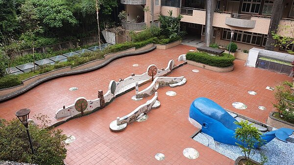 高低起伏的牆所圍成的半開放空間與公共藝術「藍鯨」。圖／麗湖國小提供