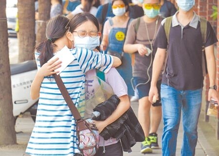 110學年度大學指考28日登場,應試人員依規定戴口罩陸續抵達考場,家長因防疫規定無法陪考,在校門口給考生擁抱鼓勵。(姚志平攝)