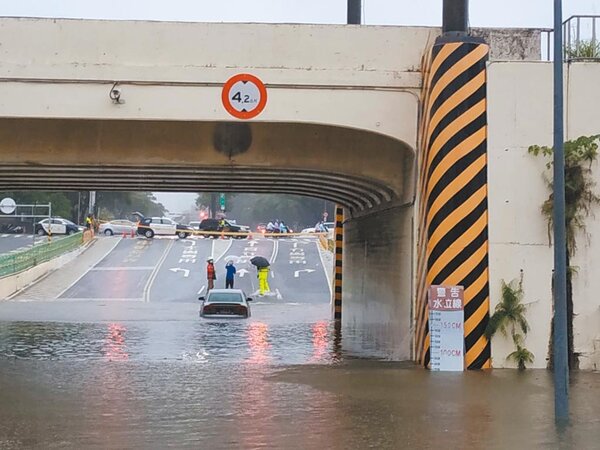 台南市小東路地下道昨天上午因暴雨積水約半個輪胎高，一輛汽車硬闖，受困水窪中等待救援。圖／讀者提供