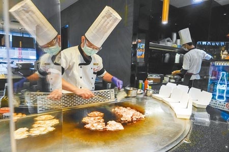 雙北、宜蘭宣布今起開放餐廳內用，圖為台北一家鐵板燒店長正在烹調客人預訂的便當，座位區已架設透明壓克力板，準備迎接客人內用。（黃子明攝）