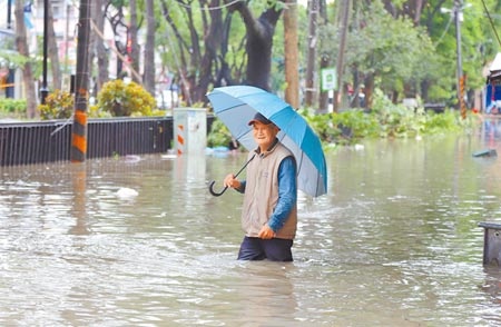 嘉義縣新港鄉2日累積雨量逾300毫米，奉天宮前中山路一帶積淹水嚴重，水深一度達到成人的大腿高度，讓居民也不禁苦笑。（呂妍庭攝）
