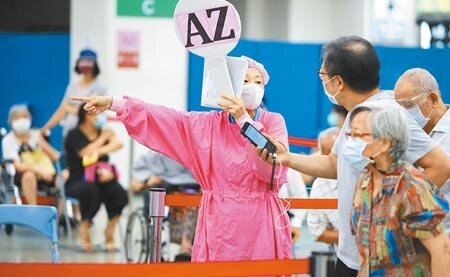 雙北20日再新增2例本土確診案,新北市衛生局說,個案居隔第4天陰轉陽對社區幾乎沒有影響。圖為護理師高舉寫有AZ的牌子指揮民眾入座施打疫苗。(本報資料照片)