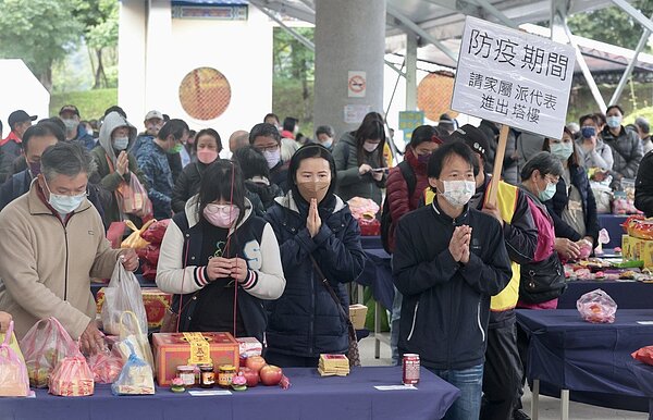 本土個案連續3天破百,但指揮中心防疫原則仍為「趨近正常生活的積極抗疫」,清明連續假期第二天,台北市富德公墓湧進大批掃墓民眾,一旁工作人員則高舉告示。記者黃義書/攝影