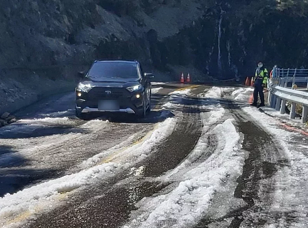 今天氣溫回升且未降雨,合歡山「水晶宮」路段卻因路旁側溝遭落石阻斷,雨水溢流路面而結冰,預估中午過後才能消融。圖/仁愛警分局提供