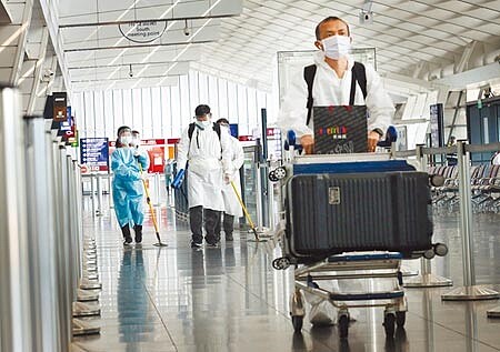近期自越南入境旅客的陽性率偏高,中央流行疫情指揮中心昨宣布,擴大所有越南來台航班的旅客,自4月9日起至5月6日止,須檢附「搭機前6小時內抗原快篩報告」,圖為桃園機場第一航廈入境大廳內,身穿防護衣的旅客準備搭車離開,清潔人員在後方消毒環境。(范揚光攝)