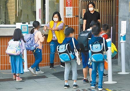 新冠疫情再起,相關足跡燒進校園,不少學校都紛紛宣布停課或改為線上教學,但有不少停課的學校陸續復課,學生進入校園前必須在大門口使用酒精噴霧消毒雙手。(張鎧乙攝)