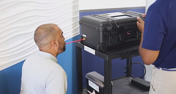 民眾透過一台「InspectIR COVID-19 Breathalyzer」呼吸檢測儀進行新冠病毒篩檢。圖／擷自InspectIR Systems官網