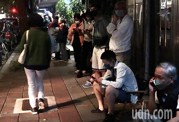 疫情延燒,快篩實名制第2天,民眾擔心周末到藥局購買撲空。29日晚台北市松山區一藥局前,民眾忍著肚子餓,大排長龍等晚上藥局開賣。記者林俊良/攝影