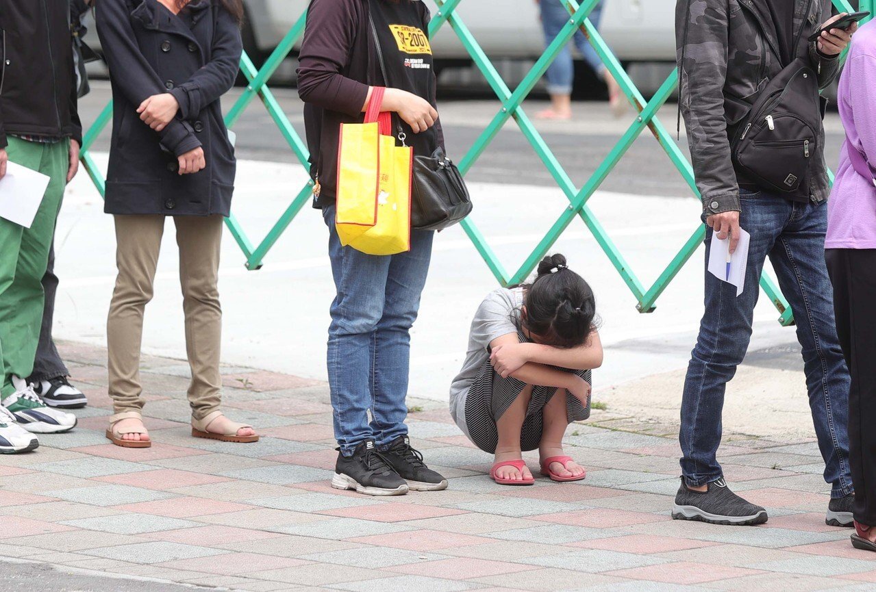 施景中表示,醫院為收治確診寶寶,恐壓縮其他重症兒童的醫療需求,是該滾動式檢討。圖為孩童跟著大人排隊等快篩。記者葉信菉/攝影