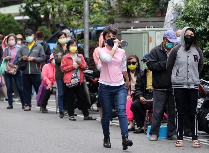 本土疫情嚴峻,快篩試劑需求暴增。圖為新北市一家藥局外,購買快篩試劑民眾排隊近百公尺,藥局工作人員手持小麥克風發放號碼牌情景。圖/聯合報