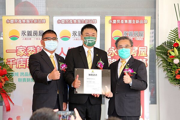 永慶房產集團加盟事業體董事長劉炳耀（右）和總經理莊志成（左）頒授權書給永義房屋全台第一家加盟店店東吳浩銘（中）。圖／永慶房產集團提供