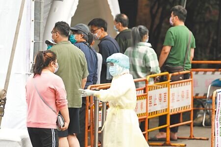 新冠肺炎疫情持續升溫,台北市七大社區篩檢站10日有許多民眾等待篩檢或前往防疫急門診,醫護人員穿著全套防護服在大太陽下指引動線。(杜宜諳攝)