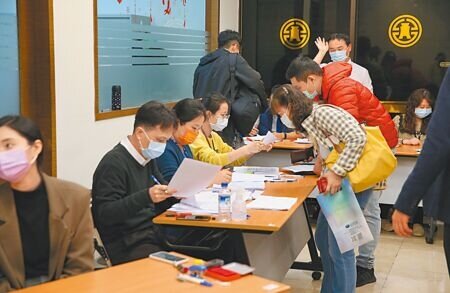 壽險公會昨同意以「數位新冠病毒健康證明」作為COVID-19診斷證明書的替代文件,但各產險公司仍未達成共識。圖為民眾購買防疫保單,工作人員忙著審查送件。(陳君瑋攝)