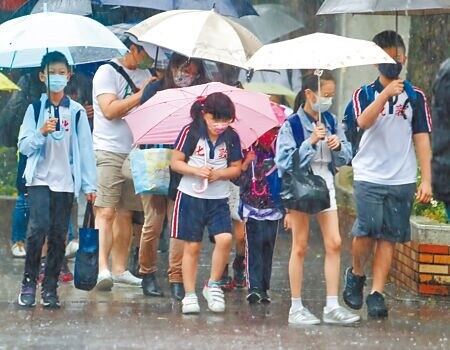 圖為學生們冒著滂沱大雨，撐著雨傘上學。（季志翔攝）