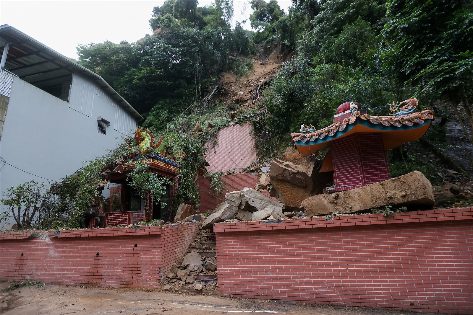 今年首波梅雨鋒面來襲，新北市石碇西街邊坡大量土石坍塌，砸毀山腳土地公廟。 同時還壓爛車輛，鄉公所擔心雨勢不歇恐再崩塌。記者余承翰／攝影 