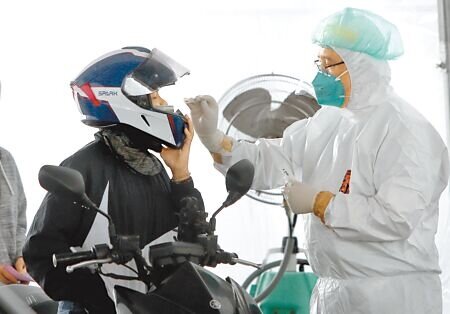 北士科快篩陽車來速篩檢站,15日持續提供快篩陽性者PCR篩檢與拿藥服務,一位騎機車的民眾掀開安全帽接受採檢。(鄭任南攝)