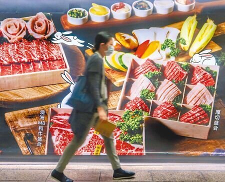 疫情攀升衝擊餐飲業，經濟部推出餐飲行銷補助，但對於行銷經費才編列6億元，不分黨派委員都憂心錢不夠。圖為民眾走過餐飲廣告看板。（本報資料照片）