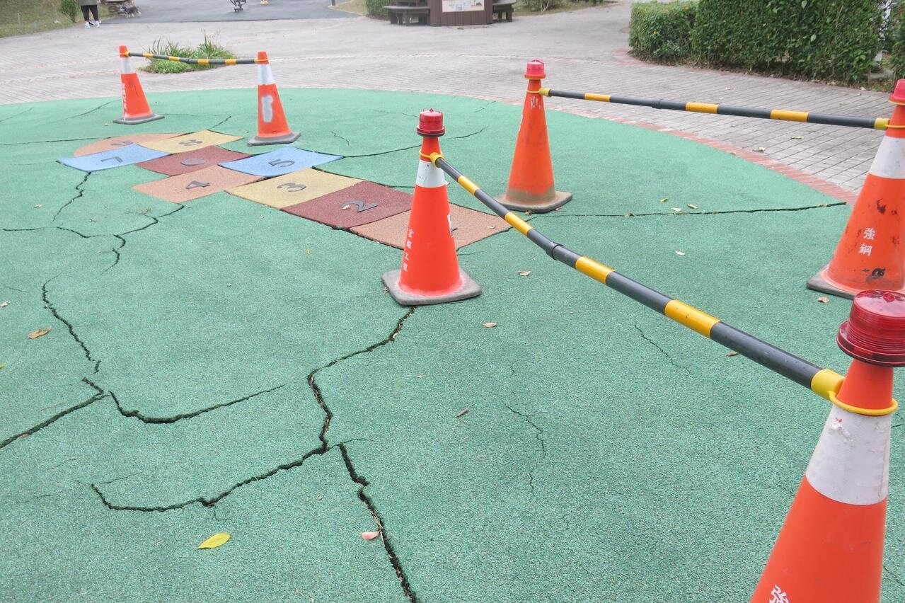 新北市中和區員山公園的地墊出現許多凹洞及裂痕,區公所先以路障封鎖,提醒民眾勿靠近。記者李成蔭/攝影