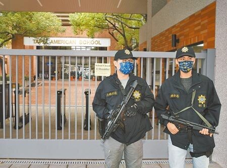 台北美國學校驚傳收到不明人士的威脅揚言開槍，校方緊急發出通知書13日預防性停止上課一天，士林分局刑警持MP5衝鋒槍站在校門警戒。（陳怡誠攝）