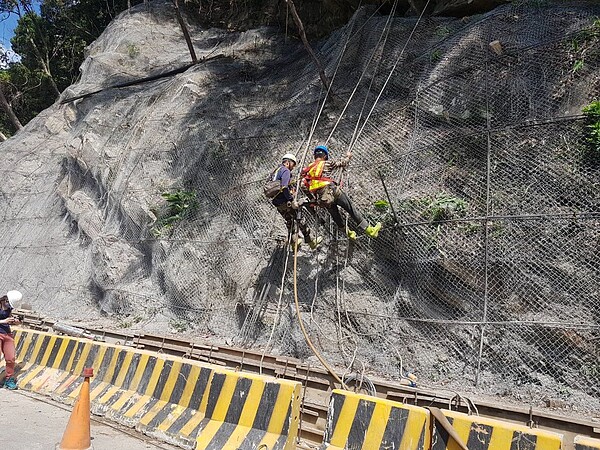 專業的邊坡蜘蛛人施工團隊,裝載個人防護用具並繫掛安全母索及工作繩進行攀爬,以兩人為一組進行施工作。圖/新北市政府提供