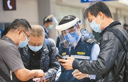 桃園發生防疫旅館群聚感染,疫情指揮中心16日宣布,強化春節入境專案篩檢次數。圖為桃機防疫人員協助入境旅客上網登錄。(范揚光攝)