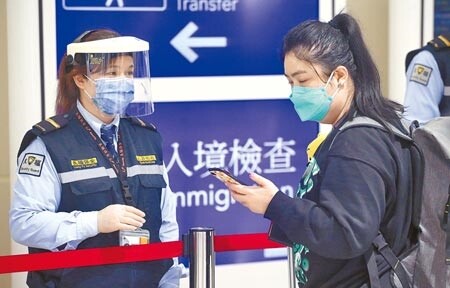 繼桃園之後，台北市防疫旅館也出現群聚染疫。圖為在桃園機場入境管制區內，防疫人員協助剛下機的旅客登錄入境檢疫資料。圖中人非新聞當事人。（范揚光攝）