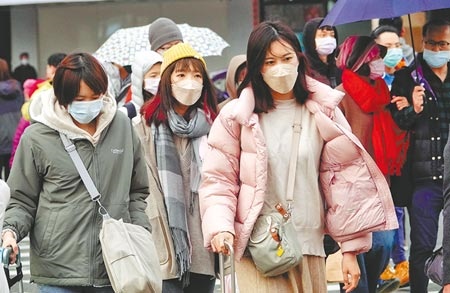 受到冷氣團和華南雲雨區影響，26日全台氣溫下降，民眾外出穿上厚重大衣禦寒。（陳信翰攝）