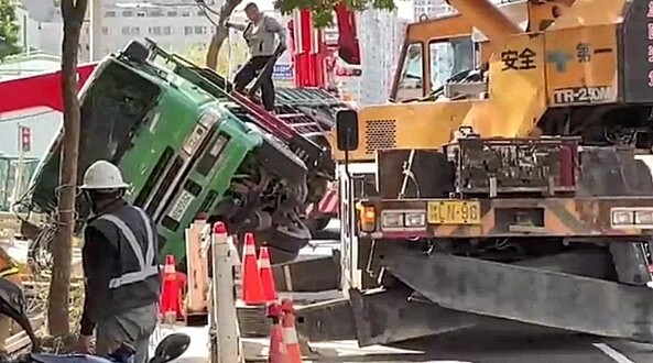 新北市板橋區南雅南路二段與遠東路口一處營建工地，疑水泥未乾，今天上午吊車進行吊掛作業時，整車傾倒翻覆，工地緊急找來二部大型吊車到場吊起傾倒的吊車，幸無人傷。圖／聯合報