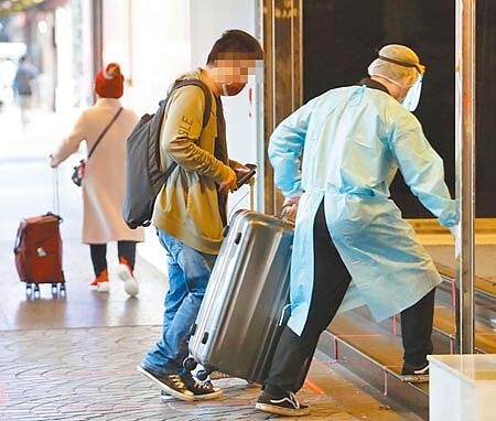 北市中正區某防疫旅館3例Omicron確診病例,疫情指揮中心昨判斷感染源為自美國返台的案17085,所以將另2例境外移入個案改判為本土,為國內首起Omicron本土確定病例。該防疫旅館也從防疫旅館名單退場。圖為旅客在防疫人員協助下進入防疫旅館。示意圖與新聞無關。(季志翔攝)