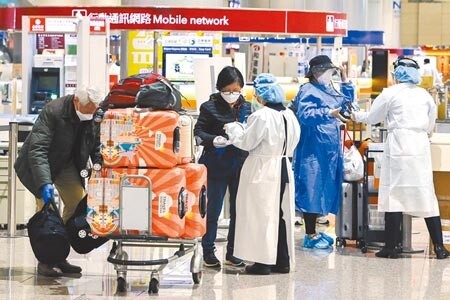 桃園機場群聚引爆本士疫情，各地加強防疫。圖為桃園機場第一線協勤人員穿著防水隔離衣協助入境旅客。（陳麒全攝）