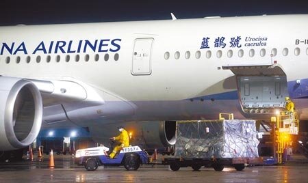 由台積電、鴻海永齡基金會及慈濟基金會共同捐贈的第16批99.45萬劑BNT疫苗,21日清晨運抵桃園機場,班機停妥後地勤人員卸下裝載疫苗的冷凍貨櫃。(范揚光攝)