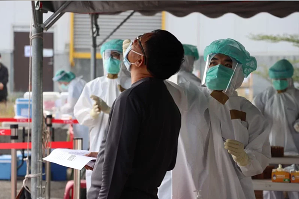 高雄港群聚感染部分再增3例,其中一例小港區民眾,因在老舊公寓停車空間與已確診的上下樓鄰居短暫接觸二、三分鐘即染疫,圖為高雄港碼頭篩檢站情形。圖/記者林巧璉翻攝