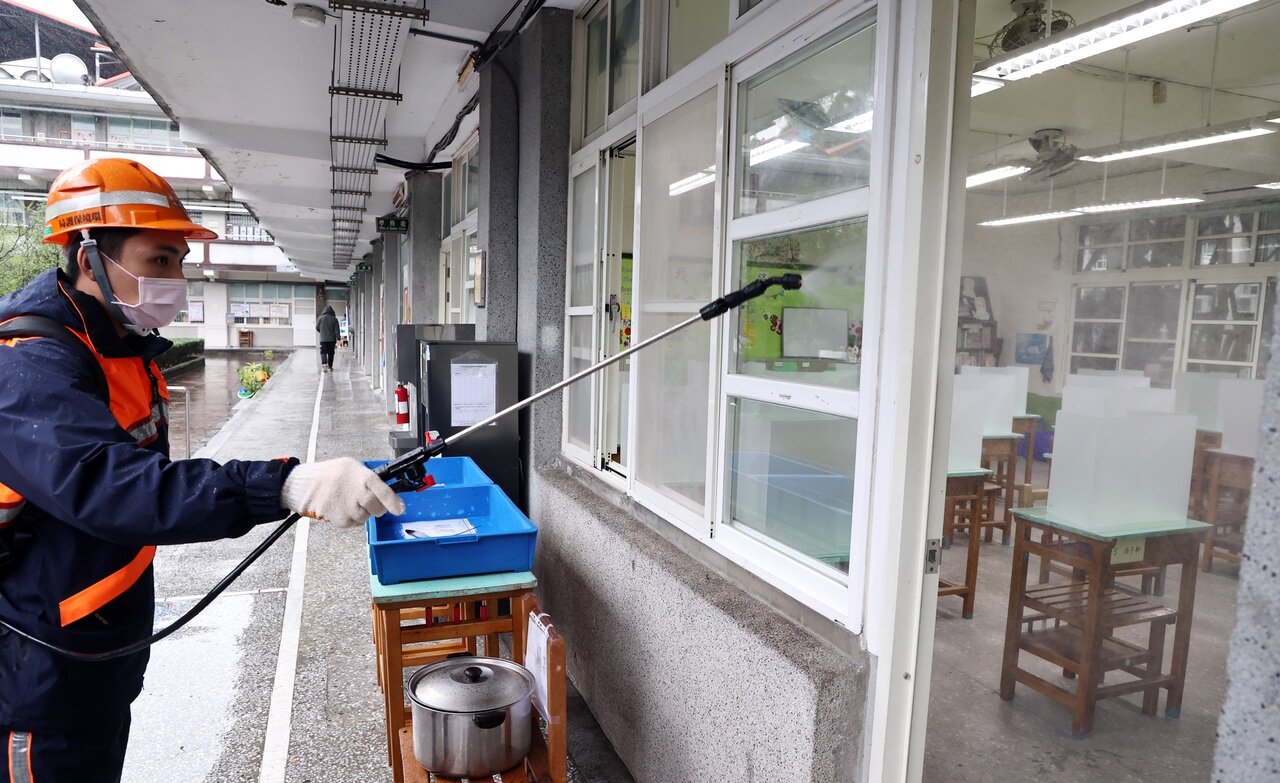 開學前夕，多名地方首長宣示「一人染疫，學校停課十四天」。新北市環保局昨派員在板橋國中教室外進行環境清消作業，校方並備妥防疫隔板。記者侯永全／攝影 