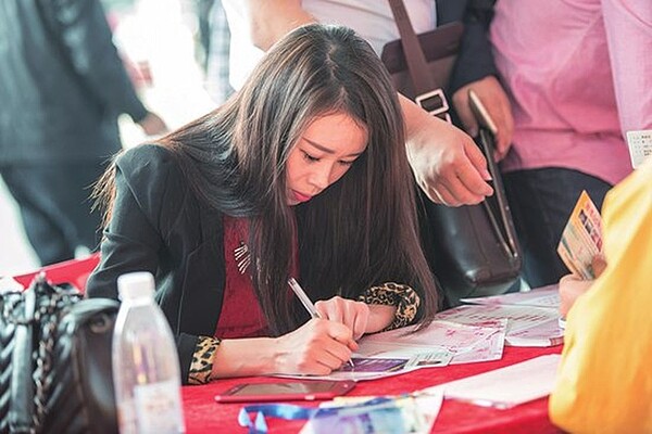 圖為東莞相親會上,一名女子在填寫資料。圖/取自中國青年報