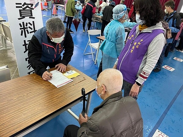 何韋翰里長在明穗里接種站協助長輩里民填寫個人資料。（圖／擷取自何韋翰個人臉書）